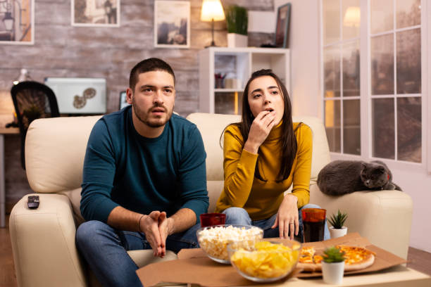 istock Couple cheering for their favourite team while watching TV 2178316532