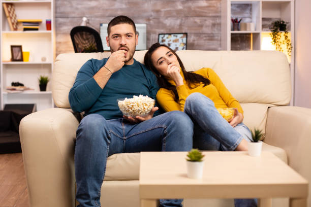 istock Handsome couple at home eating pop corn and watching TV 2178319573