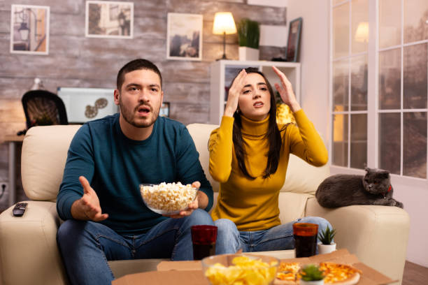 istock Couple cheering for their favourite team while watching TV 2178320181