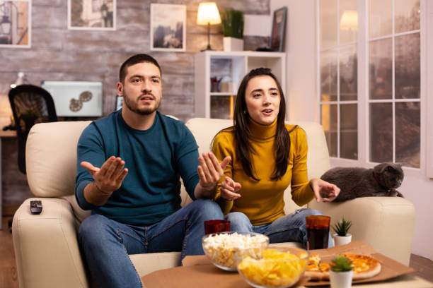 Couple cheering for their favourite team while watching TV