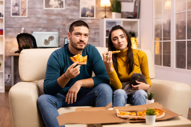 istock Gorgeous young couple eating pizza while watching TV 2178321279