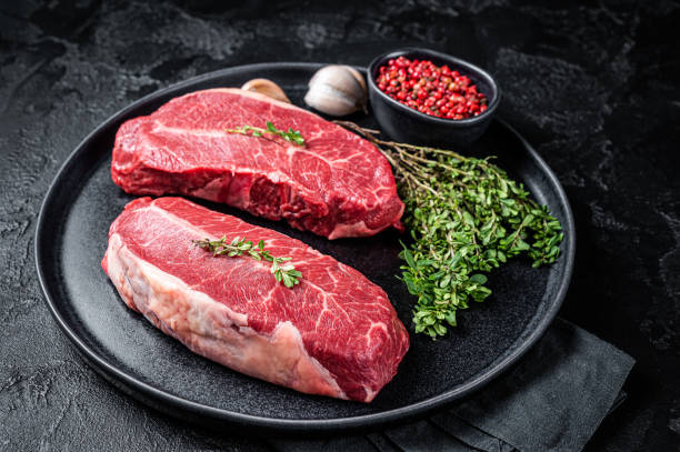 istock Dry aged Raw top blade flat Iron beef meat steaks. Black background. Top View 2178321611