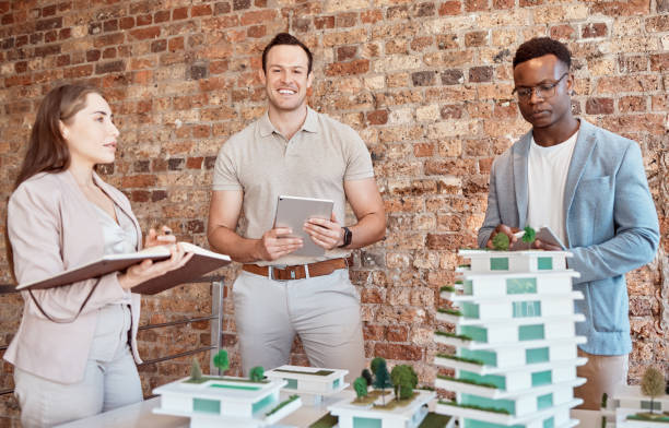 istock Group of diverse architects discussing plans, blueprints and schematics during a meeting in their office boardroom. Business people brainstorming and planning their upcoming project development 2178322184