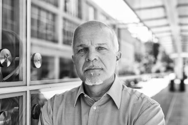 Confident senior businessman in a black and white portrait outside a modern office building. Exuding success and experience with a determined and ambitious look