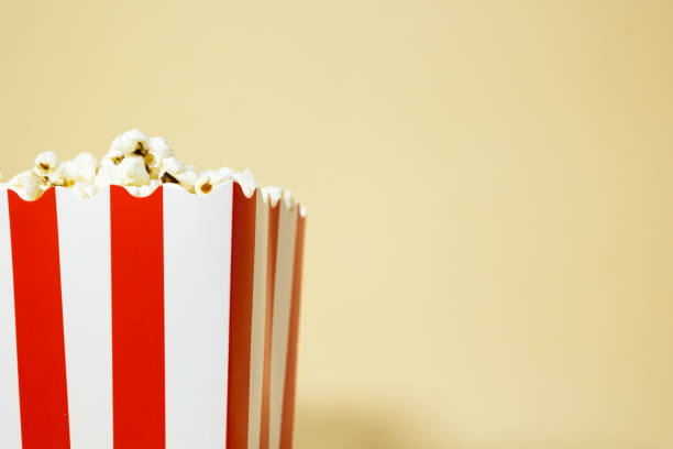 Close up of popcorn in a red cardboard carton bucket with white stripes on an isolated background, cinema food concept