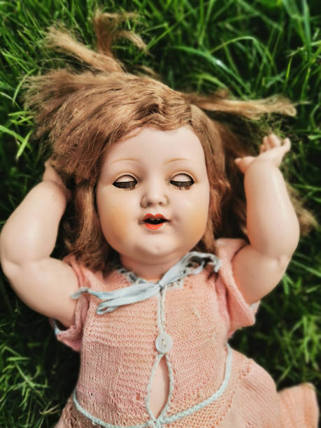 very old baby doll in the green grass