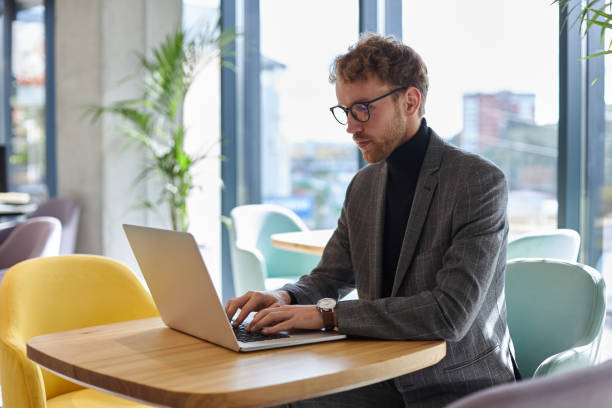 istock Young businessman working on laptop in a bright cafe 2178331359