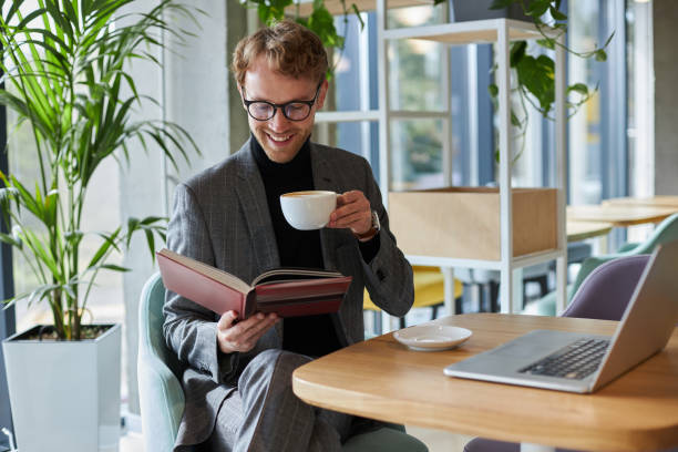 istock Happy businessman enjoying latte and reading book in cafe 2178331748