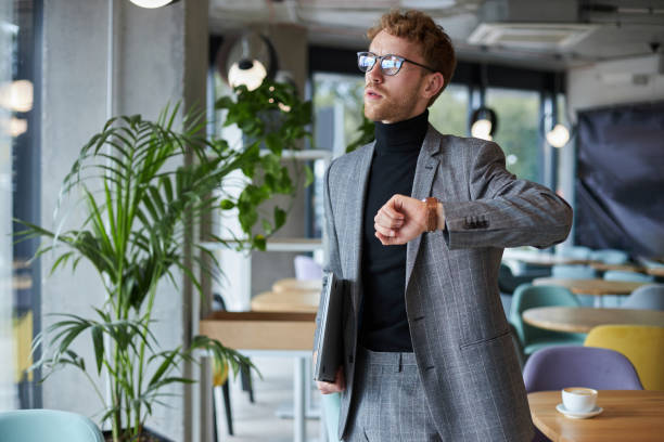 istock Businessman checking time holding laptop in cafe 2178331877