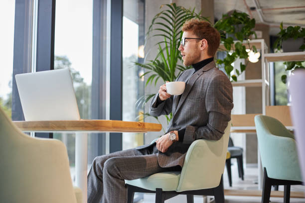 istock Elegant businessman drinking coffee and looking through office window 2178332131