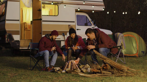 istock Man helping friend to light the camp fire in front of retro camper 2178336225