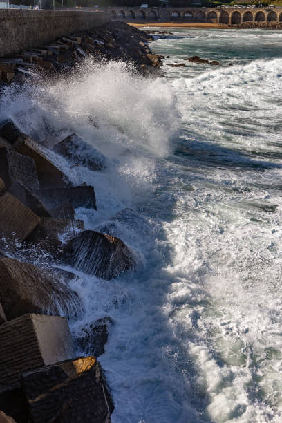 Guetaria, Spanish Basque Country, Spain. waves crashing against the seawall. The seawall is a structure built by humans to withstand and contain the force of the sea and prevent the erosion caused by the impact of waves and violent tides.