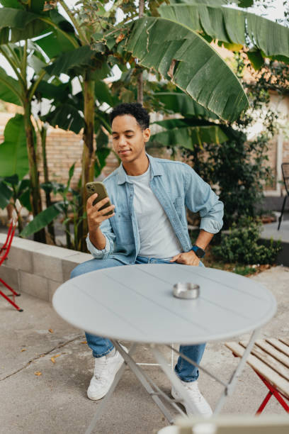 istock Man in denim shirt engaging with phone at cafe 2178336465