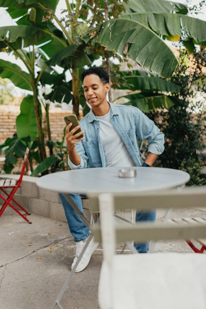 istock Man relaxed at cafe patio, focused on smartphone 2178336507