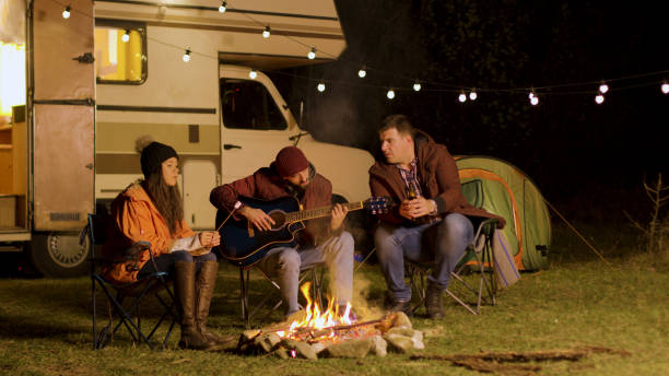 istock Man singing a song on guitar for his friends around camp fire 2178336669
