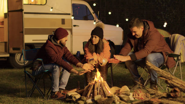 istock Close friend sitting on camping chairs around camp fire 2178337033