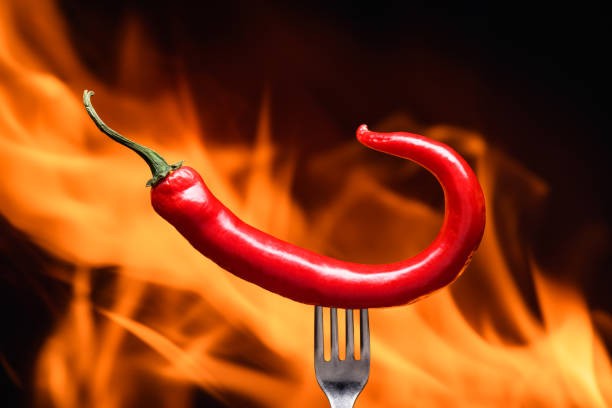 istock red chili pepper, pricked on a fork, on a background of burning fire, hot flames, on a black background 2178337319