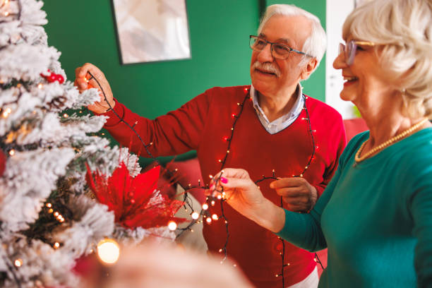 istock Senior couple placing Christmas lights on Christmas tree while decorating it 2178338194