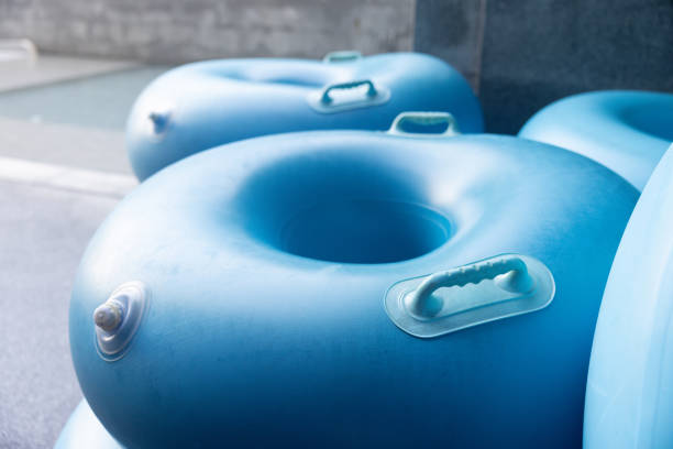 A blue inflatable pool float sits on the ground next to other blue inflatable pool floats. The pool floats are all different sizes and shapes, but they all have a similar blue color