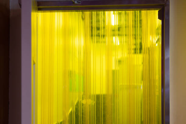 A yellow curtain is hanging in front of a door. The curtain is made of plastic and is yellow in color