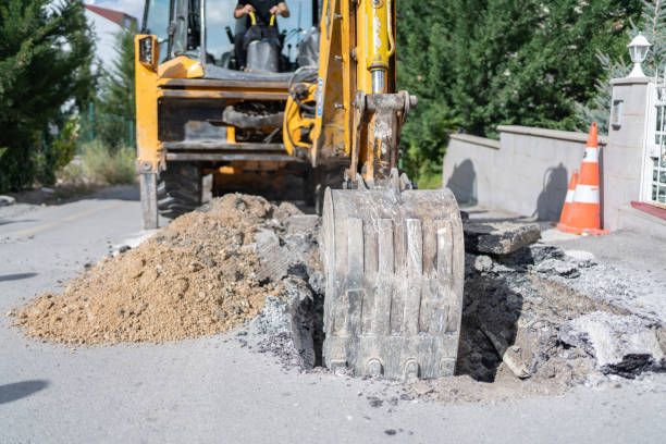 Excavator Operator Digging A Hole On Road To Pipeline Replacement On The City Street