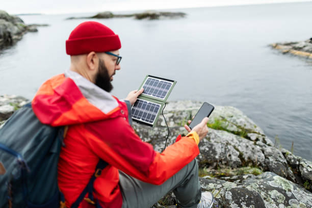 istock Mid adult man hiking in mountains with solar panel and charging mobile 2178341843