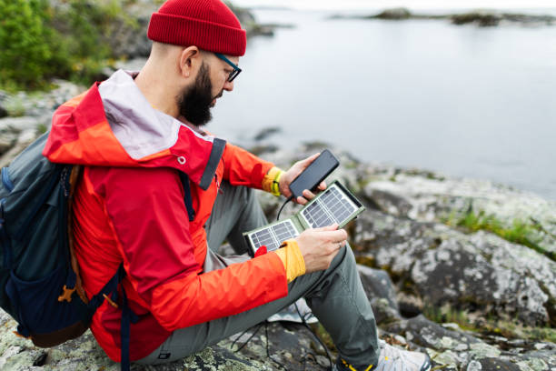 istock Mid adult man hiking in mountains with solar panel and charging mobile 2178341844