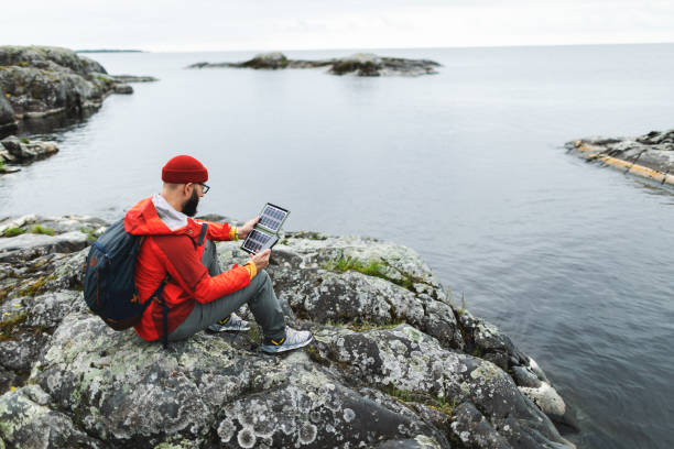 istock Mid adult man hiking in mountains with solar panel and charging mobile 2178341846