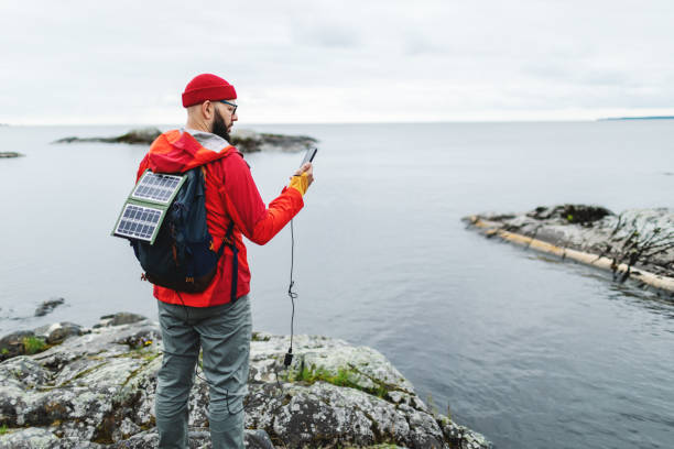 istock Mid adult man hiking in mountains with solar panel and charging mobile 2178341871