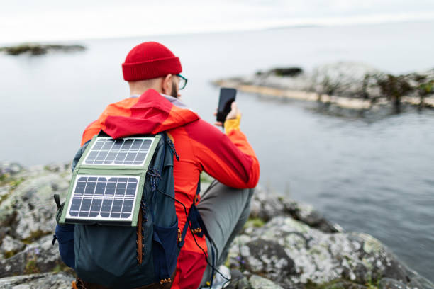 istock Mid adult man hiking in mountains with solar panel and charging mobile 2178341886