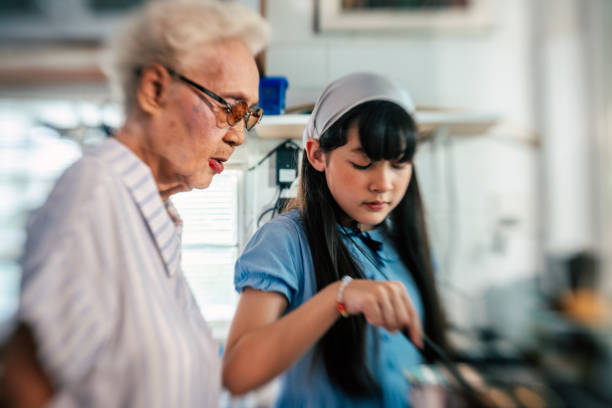 Teenage girl helping her grandmother while cooking in the kitchen at home