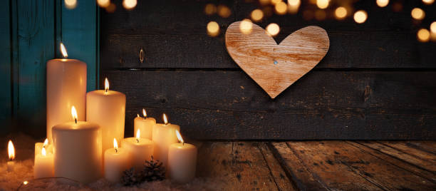 Burning candle lights on dark old wood
