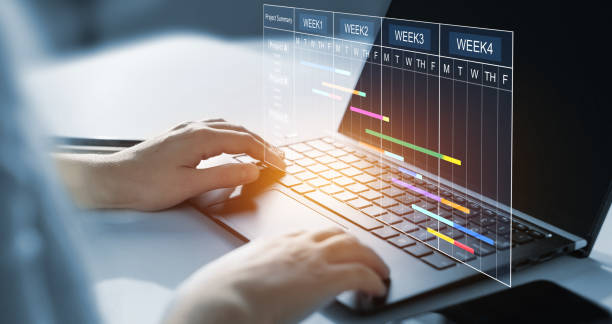 Project manager working on laptop and updating tasks and milestones progress planning with Gantt chart scheduling interface for company on virtual screen.  Business Project Management System.