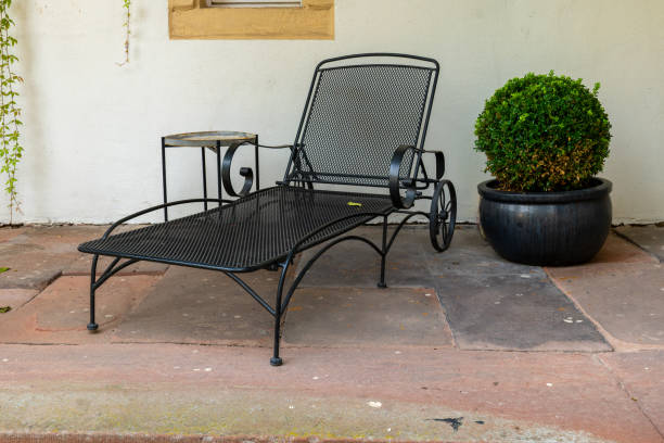 A black metal lounge chair sits on a patio outside a building stock photo