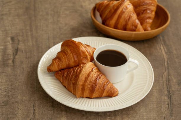 Closeup of autumn breakfast with hot croissant. Female hands holding a cup of hot chocolate. Fall.