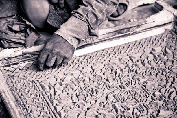 A skilled worker sands a wooden block in a workshop, focusing intently on his craft on a well-lit workbench. The atmosphere conveys dedication, craftsmanship, and a passion for woodworking artistry.