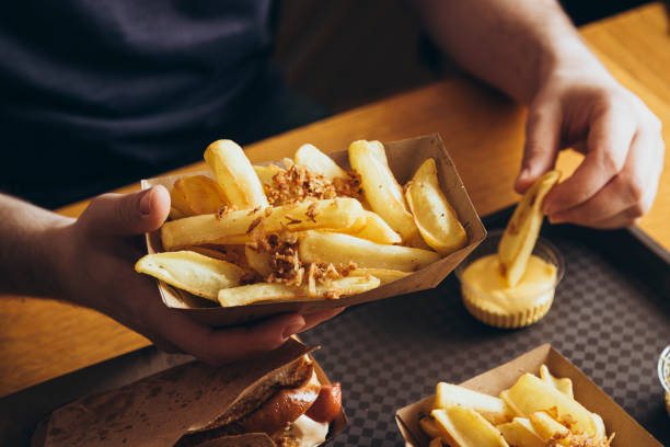 istock A man eats crispy potatoes with cheese sauce in a pub or fast food cafe. 2178365844
