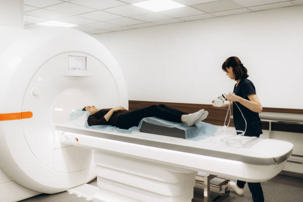 istock Patient is getting recommendations from doctor before MRI procedure. Woman is lying down at CT scanner bed. Female is moving into MRI scanner capsule. Female doctor is conducting tomography examining. 2178368900