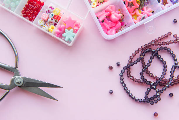 istock Crafting supplies spread out on a pink surface featuring beads, scissors, and accessories organized in containers 2178369015