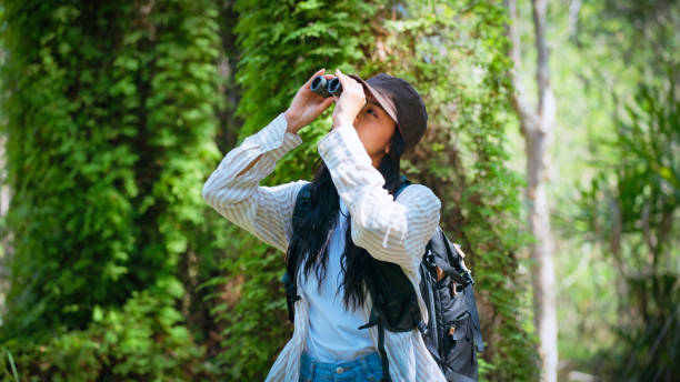istock Trendy young woman using binoculars in the woods 2178371764