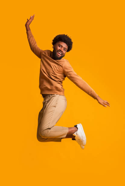 istock Positive afro guy jumping up over orange background 2178373890
