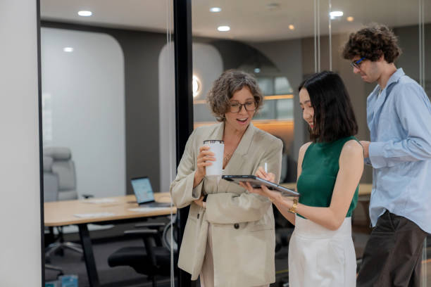 istock A group of financial analysts walk through a modern office, holding digital tablets and engaging in conversation. The sleek, professional environment features glass-walled conference rooms, highlighting an atmosphere of collaboration and corporate culture 2178376675