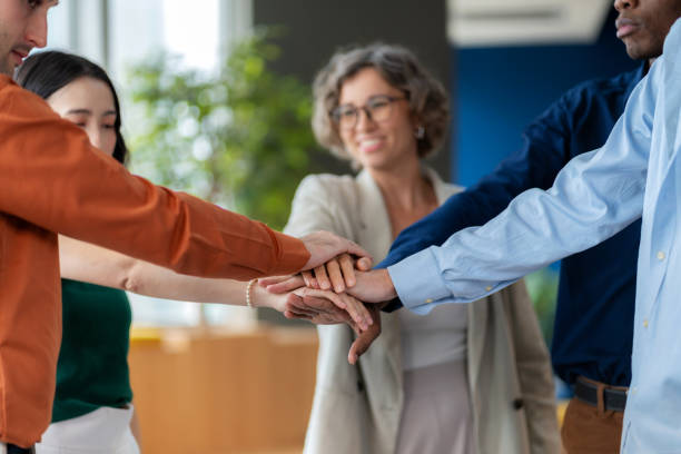 istock A diverse group of startup employees, dressed in casual clothing together and stack their hands as a symbol of teamwork, harmony, and collaboration. Positive workplace environment where unity and support drive success. Reflects motivation, trust. 2178376705