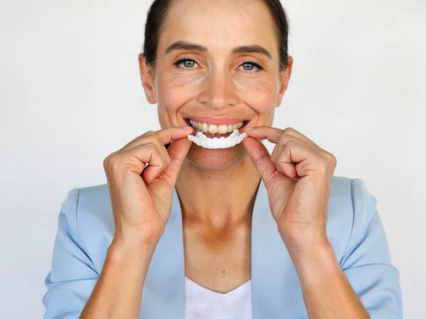 istock Woman demonstrates applying aligner while smiling 2178377293