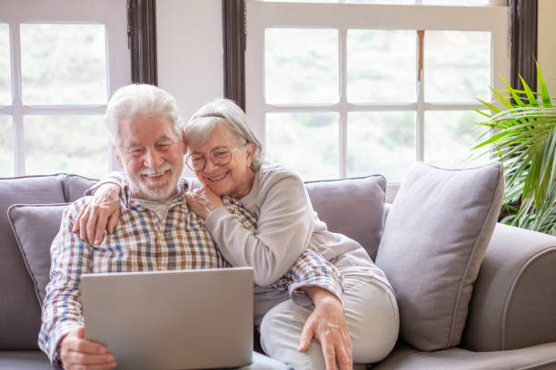 istock Happy white-haired 70-year-old couple at home using laptop together watching video. Older people use new technologies 2178381694