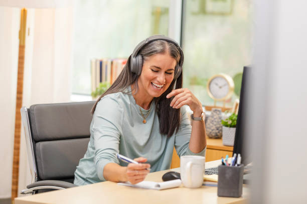 istock Mature female student smiles while listening to her classmates during their online class 2178382142