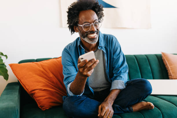 istock Happy mature man relaxing on the sofa, smiling and using a mobile phone 2178384027