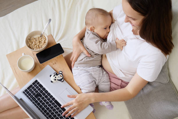 istock Brown haired woman browsing internet on portable device while breastfeeding newborn baby balancing responsibilities of telework at home and taking care of her infant son 2178384476