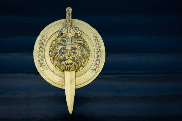 Shield with lion head isolated on dark wooden background. Royal Shield and sword in gold color. Ancient warrior shield from close-up. Nobody