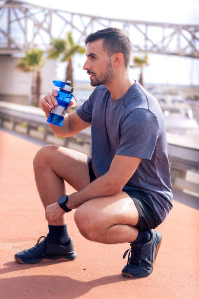 istock Side view runner man drinking water from a sports bottle outdoors. 2178388088